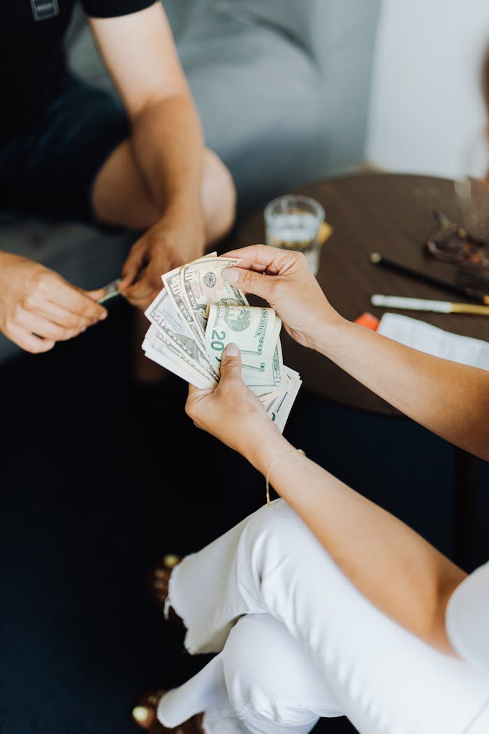 Close-up of hands counting cash in an indoor setting, conveying transaction theme.